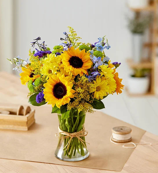 Merci/Tournesol, delphinium bleu, marguerite jaune, marguerite verte et fleur étoilée violette